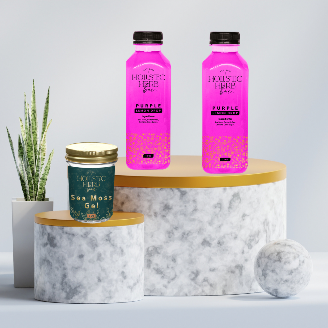 Two pink bottles of sea moss lemonade and a container of sea moss gel, displayed on a marble surface with a plant decoration in the background.