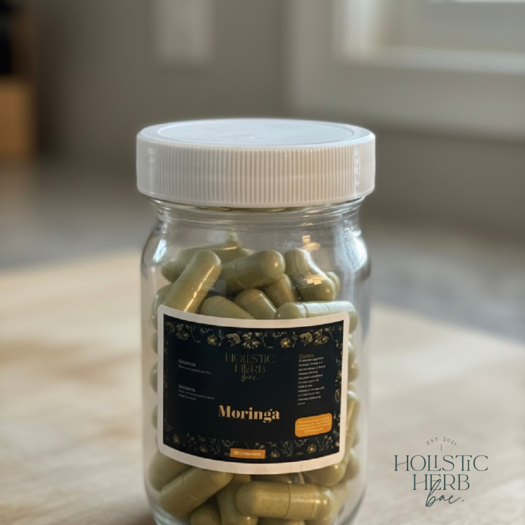 Holistic Herb Bae Moringa leaf capsules in a clear glass jar, displayed on a wooden surface for a natural wellness aesthetic.